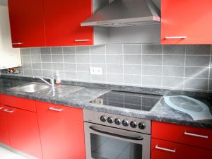 kuchnia z czerwonymi szafkami, kuchenką i zlewem w obiekcie Pension Prell w mieście Düren