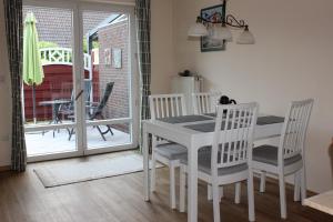 Un comedor con una mesa y sillas blancas. en Haus Deichbrise, en Niebüll