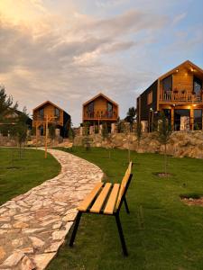 萨维奇أكواخ الصنوبر的坐在建筑物前面的草上的一个长凳