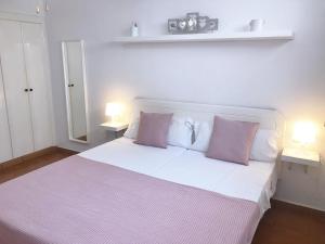 a bedroom with a white bed with two pink pillows at Apartamento Helena en Garden City con piscina climatizada in Playa Fañabe +75 photos