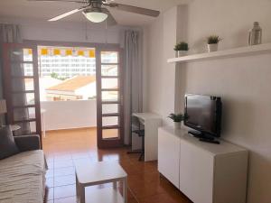 a living room with a couch and a tv in it at Apartamento Helena en Garden City con piscina climatizada in Playa Fañabe