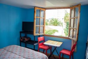 a bedroom with a bed and a table and two red chairs at Hostal EntreOrientes in Viña del Mar