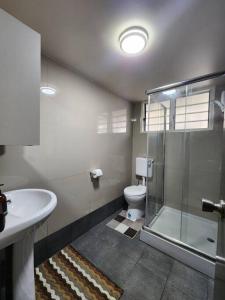 a bathroom with a shower and a toilet and a sink at The City Edge in Vatuwangga