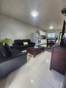a living room with black couches and a kitchen at The City Edge in Vatuwangga