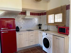 eine Küche mit einem roten Kühlschrank und einer Waschmaschine in der Unterkunft Casa Rural Sierra Norte 68 in El Ronquillo