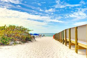 a beach with benches on the sand and the ocean at New! Remodeled, Pool-Side, 1-min to Beach Path! in Siesta Key