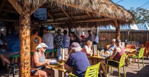 a group of people sitting at tables under a straw umbrella at New! Remodeled, Pool-Side, 1-min to Beach Path! in Siesta Key