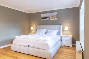 a white bed in a bedroom with two lamps at Gutshof-Penthouse-Wohnung- Seeblick in Klein Upahl +31 photos