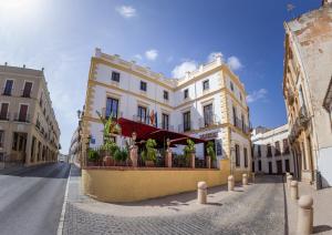 a white building with a red awning on a street at Hotel Palacio de Hemingway in Ronda