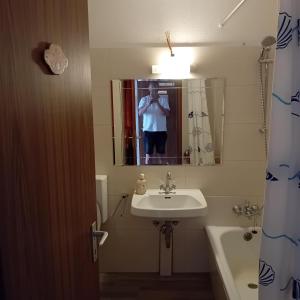 a man taking a picture of a bathroom with a sink at Ferienwohnung Oshowski in Berchtesgaden