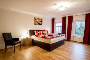 a bedroom with a bed and a chair and red curtains at Gutshofwohnung Hofblick in Klein Upahl