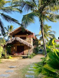 a house with a straw roof and a palm tree at Pousada kaz'oca in Icaraí