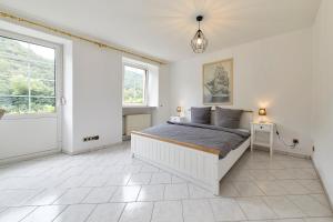 a white bedroom with a bed and a window at Haus am Hafen in Bernkastel-Kues