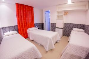 a room with three beds and a red curtain at Vivaz Boutique Hotel in Recife
