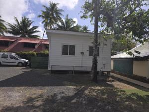 a white house with a tree in a driveway at SARL FARE MOOREA in Moorea