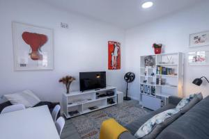 a living room with a couch and a tv at The Dolls House in Cape Town