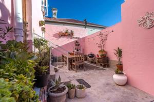 a patio with a pink building with a table and potted plants at The Dolls House in Cape Town