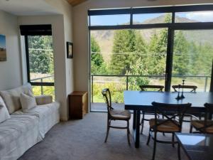 salon z kanapą, stołem i krzesłami w obiekcie Coronet Queenstown Escape w mieście Frankton