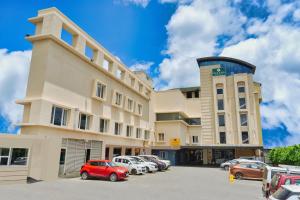 苏丹巴特利mesta Hotel的一栋建筑物,停车场里停着几辆车