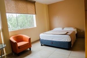 a bedroom with a bed and a chair and a window at TruGarden Hotel Trujillo in Trujillo