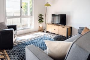 a living room with a couch and a flat screen tv at Sandy Shores in Inverloch