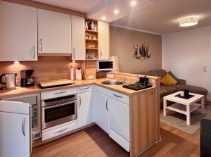 eine Küche mit weißen Schränken und einem Sofa in der Unterkunft Residenz am Yachthafen, Whg 4 in Grömitz