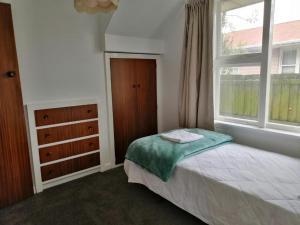 a bedroom with a bed and a window and a dresser at Homestay Family rooms Near city center in Christchurch