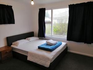 a bed in a room with a large window at Homestay Family rooms Near city center in Christchurch