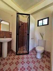 een badkamer met een douche, een toilet en een wastafel bij Gold View Beachfront Resort in Timbaon