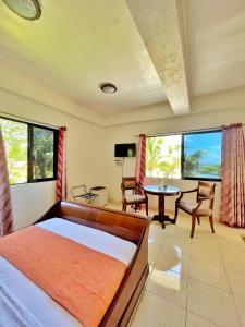 een slaapkamer met een bed, een tafel en stoelen bij Gold View Beachfront Resort in Timbaon +91 foto's