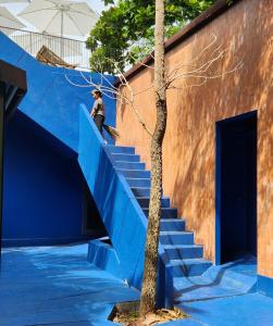 a man climbing a blue staircase next to a building at hiddenwoods in Bang Chak