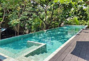 a swimming pool with blue water and trees in the background at hiddenwoods in Bang Chak