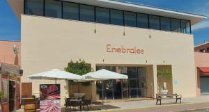 Un edificio con mesas y sombrillas delante. en Enebrales Home, en Punta Umbría