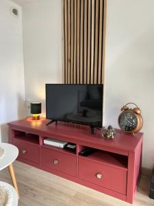a red entertainment center with a flat screen tv on it at Maisonnette centre de Wimereux, parking gratuit, 200m plage in Wimereux +5 photos