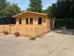 a wooden cabin with a fence in a yard at Oak Tree Cabin in Caldicot