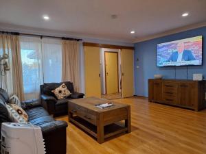 a living room with a couch and a flat screen tv at Comfy 3 bed house in Ulladulla in Ulladulla