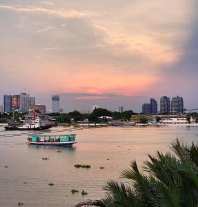a boat on a river with a city in the background at hiddenwoods in Bang Chak