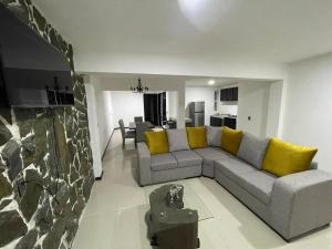 a living room with a gray couch and yellow pillows at Hospedaje Chignahuapan in Chignahuapan