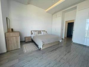 a white bedroom with a bed and a wooden floor at Gammarth touristique Penthouse in Gammarth