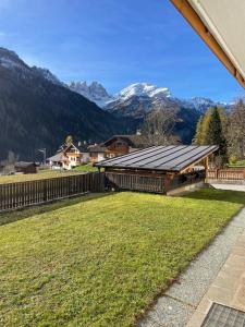 a large yard with a fence and mountains in the background at Appartamento Canes in Caviola