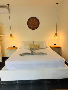 a bedroom with a large white bed with two lights at Santai Retreat in Kuta Lombok