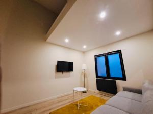 a living room with a couch and a tv on the wall at Studio Cosy Métro 14 Paris in Orly