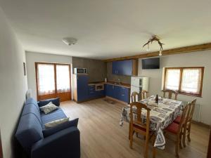 a kitchen and dining room with a table and a blue couch at Chalet Nontiscordardime in Cogolo
