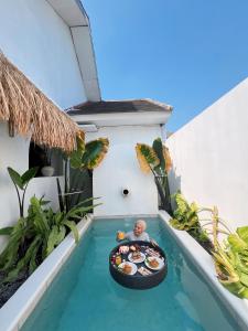 a man in a raft in a pool with food at Villa Ganesh by Suasana Villa in Jarakan