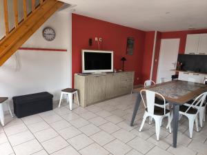a living room with a table and a television at Les Champs De La Mer in Auberville-la-Renault