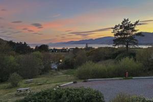 a bench in a field with a sunset in the background at 1 Bedroom Cabin with Mountain & Loch Views - Quiet Location between Glencoe & Ben Nevis in Corran +40 photos