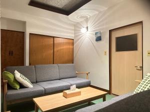 ein Wohnzimmer mit einer Couch und einem Tisch in der Unterkunft ファミリー仲良しグループ向け一棟貸切の宿ともだちハウス in Chichibu