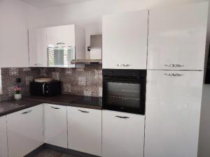 a kitchen with white cabinets and a black oven at Villa Niko in Porat