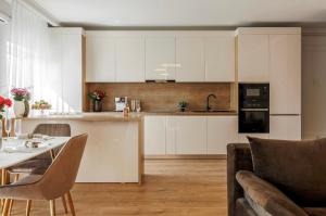 a kitchen with white cabinets and a table and chairs at Smarald Luxury Apartment in Satu Mare