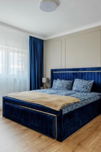 a large blue bed in a bedroom with blue curtains at Smarald Luxury Apartment in Satu Mare